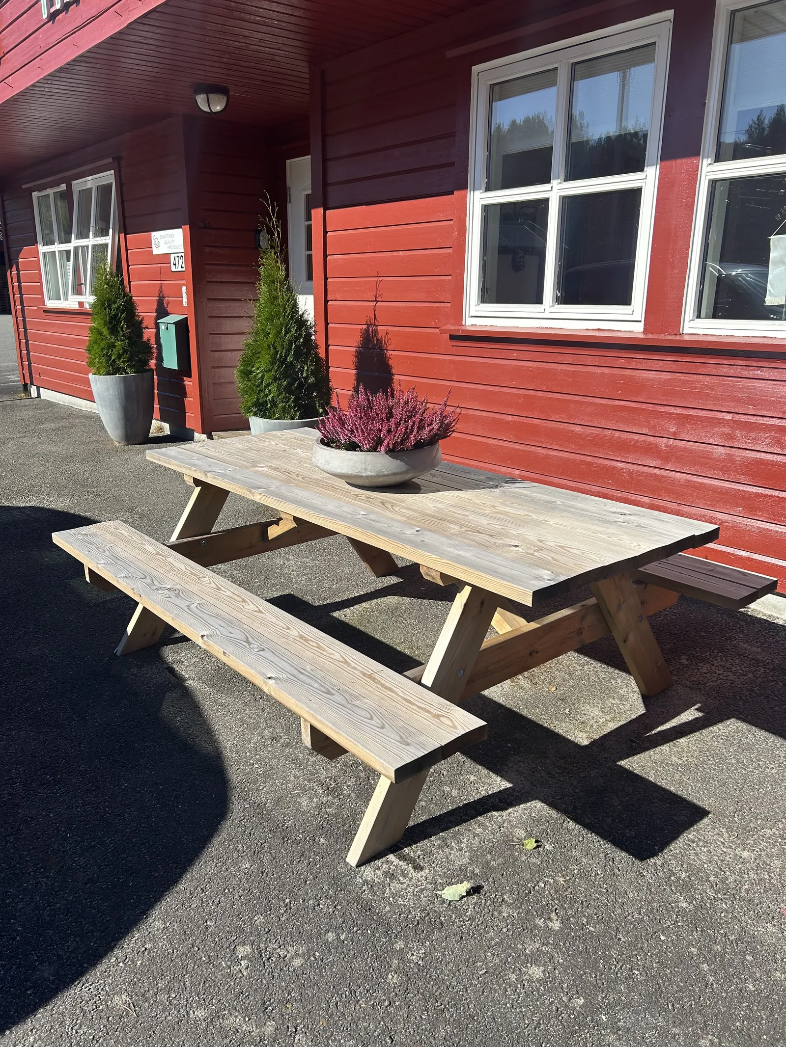 Hagebord med benker i tre foran SQPs røde bygning på Snartemo