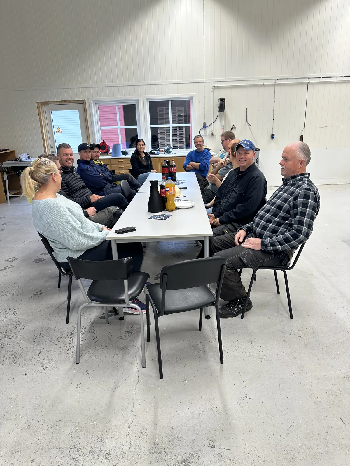 Ansatte samlet rundt et langbord i SQPs produksjonshall